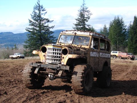 1996 Ford Bronco - Muddy off-road event with a vintage Jeep wagon and other vehicles on a dirt track.