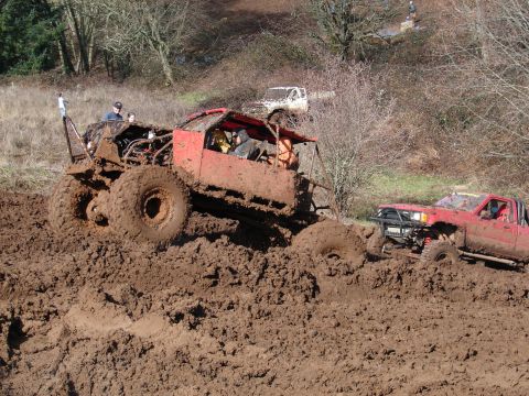 1996 Ford Bronco - Two off-road vehicles are deeply stuck in thick mud during an event.