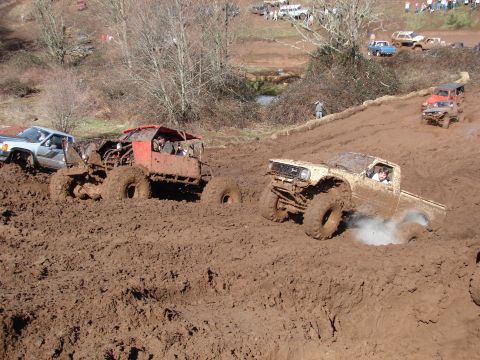 1996 Ford Bronco - Multiple vehicles navigate a challenging mud pit during an off-road event.