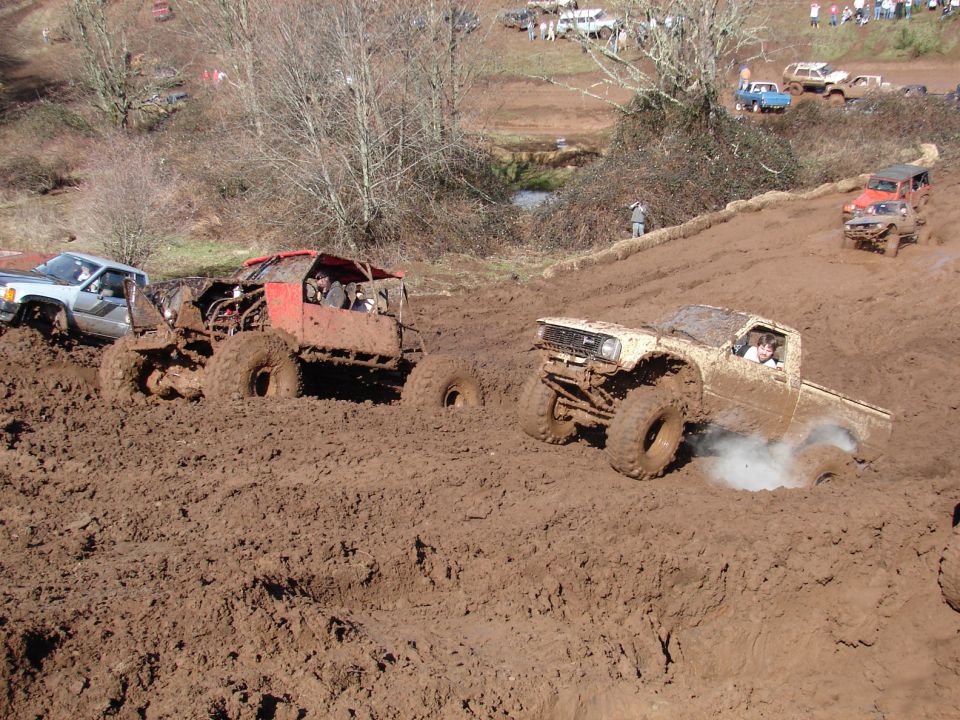 Mud bogging event with several off-road trucks and buggies stuck in deep mud
