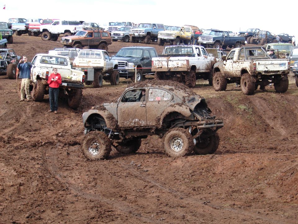Mud-covered Volkswagen Beetle with lifted suspension and off-road tires