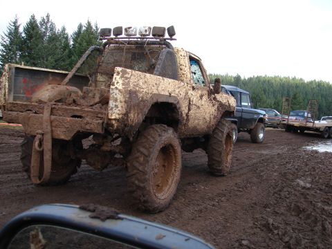 1996 Ford Bronco - Several vehicles are stuck in the mud at an off-road event, with trees in the background.