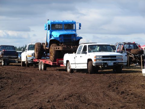 1996 Ford Bronco - Multiple trucks are gathered at a muddy outdoor event.
