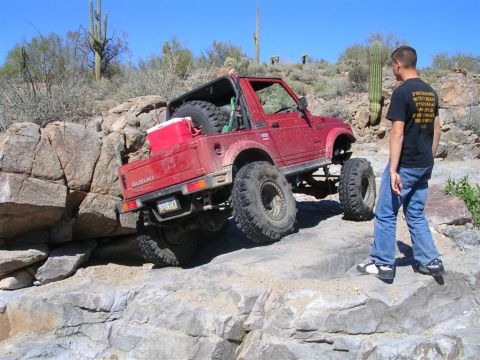 1987 Suzuki Samurai - This modified 1987 Suzuki Samurai is tackling a challenging rocky trail in a desert environment.