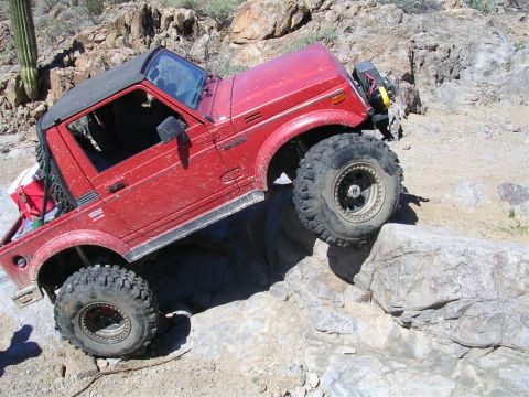 1987 Suzuki Samurai - This red 1987 Suzuki Samurai navigates a challenging rocky terrain during an off-road excursion.