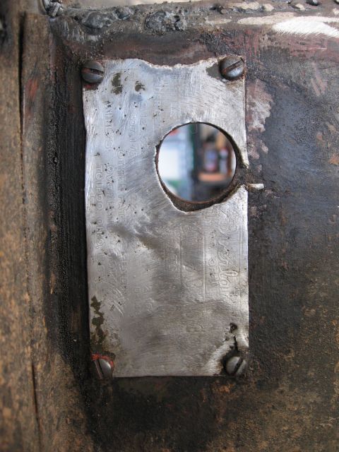 1986 Ford Bronco - A metal plate with a circular cutout is attached to a textured surface with screws.