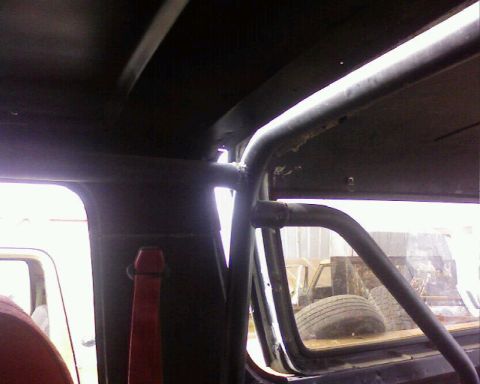 1995 Ford Bronco - The interior of a vehicle shows a prominent roll cage structure and a red seatbelt.