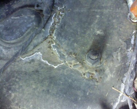 1995 Ford Bronco - Corroded metal part with a bolt, likely from a vehicle's undercarriage.