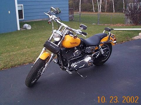1998 Ford Crown Victoria - Yellow Harley-Davidson motorcycle parked on asphalt driveway with a blue building in the background.