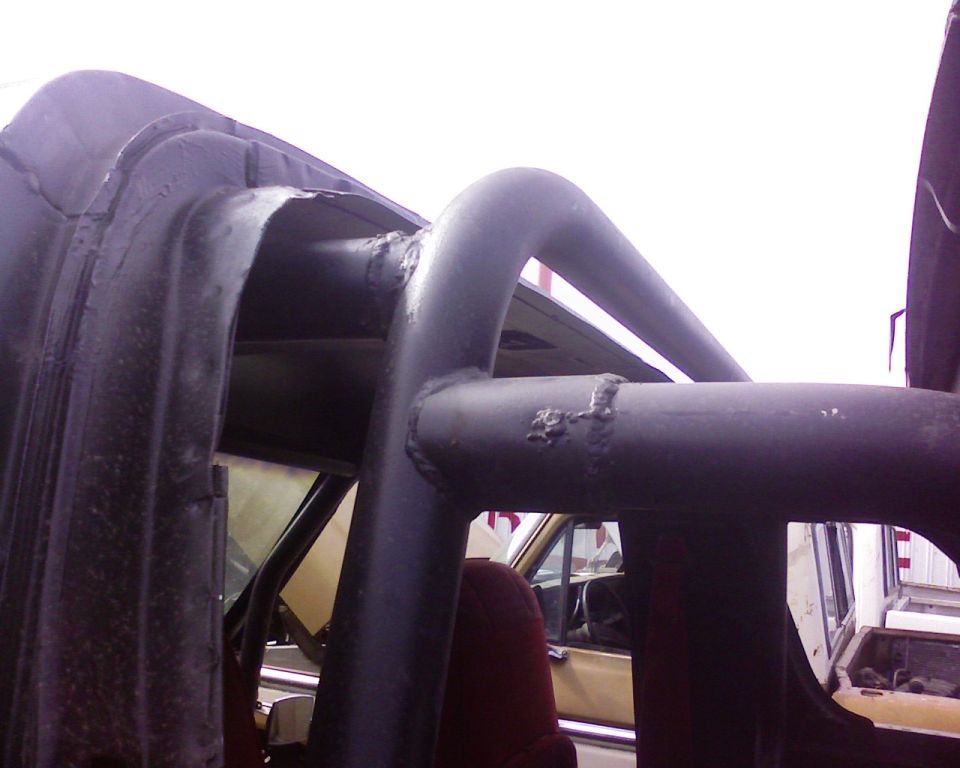 close-up of a black roll cage inside a vehicle, showing welds and tubing