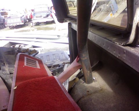 1995 Ford Bronco - Interior view of a vehicle's cabin, surrounded by scrap parts and other vehicles in a junkyard.