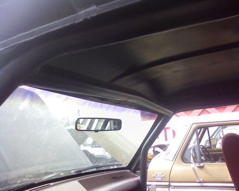 1995 Ford Bronco - The interior of a vehicle shows a roll cage structure, with another vehicle partially visible outside.