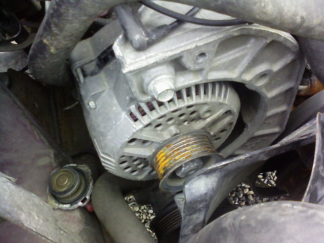 close-up of a vehicle alternator with a pulley and some hoses