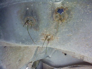 1995 Ford Bronco - Close-up view of corroded vehicle undercarriage with visible damage and exposed wires.
