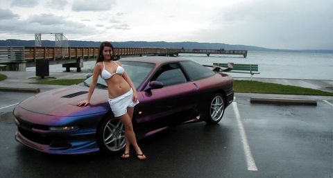 1994 Ford Probe - Custom iridescent purple 1994 Ford Probe parked near a pier with a woman posing next to it.