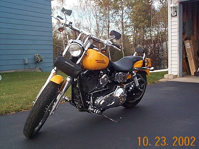 Yellow Harley-Davidson motorcycle parked on asphalt driveway in front of garage