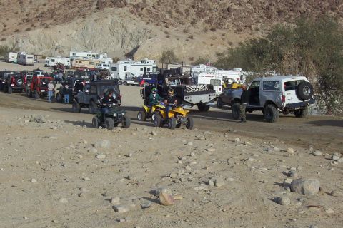 1995 Ford Bronco - A group of off-road vehicles and RVs are gathered in a desert landscape.