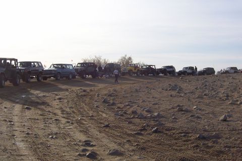 1995 Ford Bronco - A group of SUVs and trucks are gathered on a dusty, rocky terrain, with several vehicles lined up on a hill.