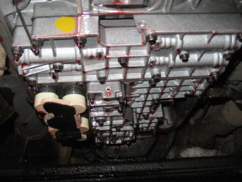 1991 Ford Bronco - Transmission pan showing fluid leaks around the bolts and a significant amount of fluid accumulation.