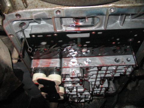 1991 Ford Bronco - Close-up view of a transmission valve body with red fluid and a dipstick inserted.