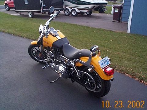 1998 Ford Crown Victoria - A yellow motorcycle is parked on a driveway with a trailer and boat in the background.