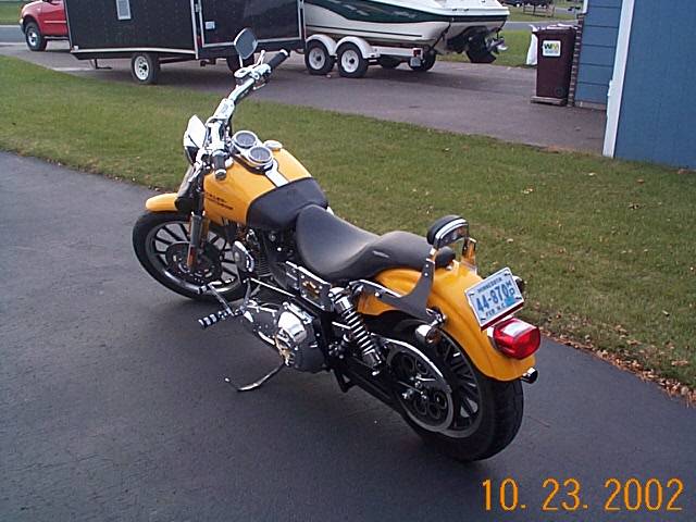 Yellow motorcycle with black seat and chrome accents, parked on asphalt