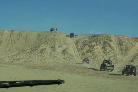 1995 Ford Bronco - Multiple off-road vehicles navigate a steep, sandy incline on a sunny day.