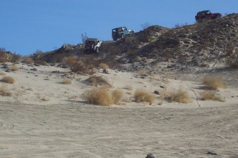 1995 Ford Bronco - Multiple off-road vehicles navigate a challenging sandy incline in a desert landscape.