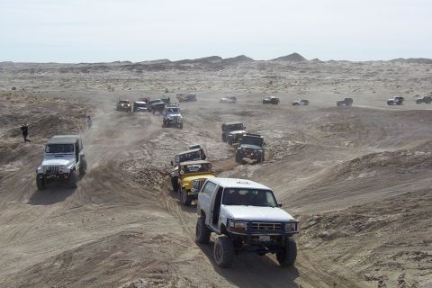 1995 Ford Bronco - A group of off-road vehicles, including a 1995 Ford Bronco, navigate a desert terrain.