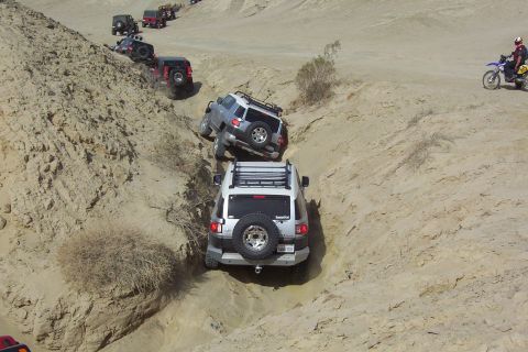 1995 Ford Bronco - A group of off-road vehicles and a motorcycle descend a challenging desert trail.