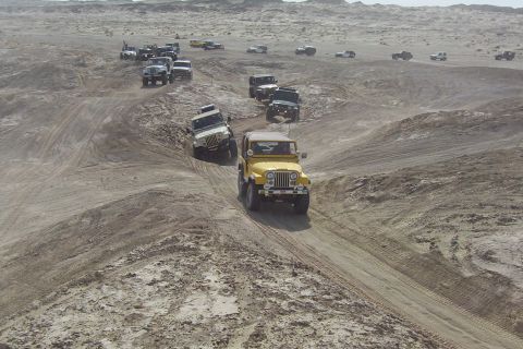 1995 Ford Bronco - A convoy of Jeeps navigates a desert landscape, kicking up dust on the sandy trails.