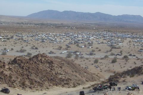 1995 Ford Bronco - A large gathering of RVs and off-road vehicles are spread across a desert landscape.