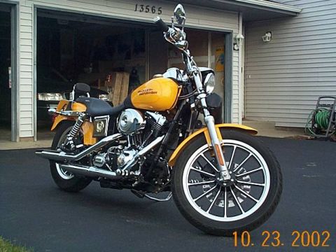 1998 Ford Crown Victoria - A yellow motorcycle is parked in front of a garage with the door open.