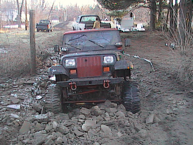 Red Jeep Wrangler with winch crawling over a rock pile