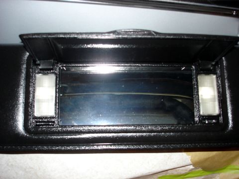 1979 Ford Bronco - The interior of a vehicle shows a black sun visor with a mirrored compartment and two lights.