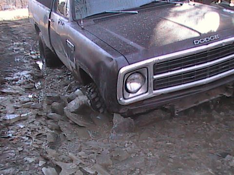 1980 Dodge Magnum - A 1980 Dodge pickup truck is stuck in thick mud, showing its front grille and headlight.