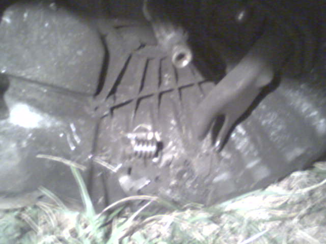 Clutch and transmission housing with a metal lever. Grassy ground below