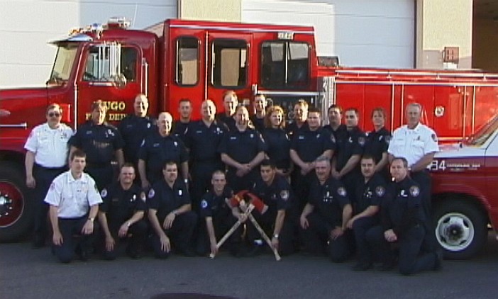 Firefighters pose in front of a red fire truck