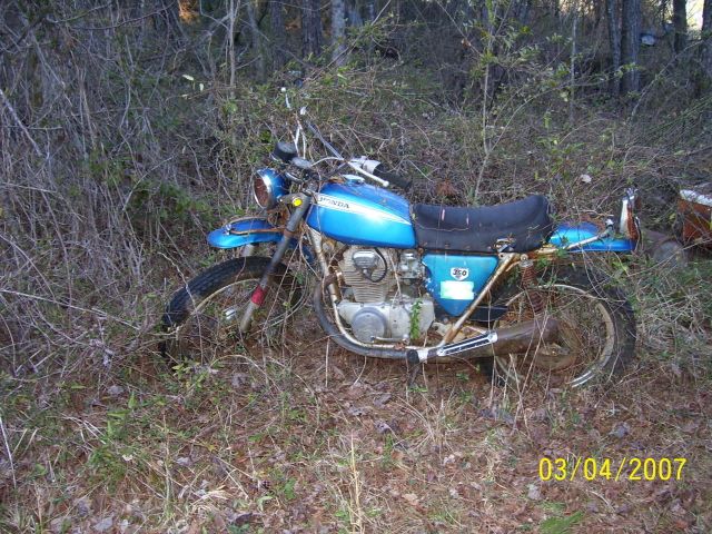 Blue Honda 350 motorcycle abandoned in overgrown brush, left side view, dated 03/04/2007