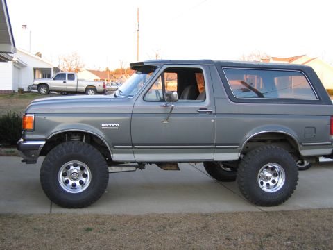 1989 Ford Bronco - This lifted Ford Bronco is shown from the side, large off-road tires and a visor above the windshield.