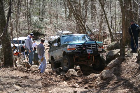 1979 Ford Bronco - Off-road enthusiasts tackle a challenging rocky trail with multiple vehicles and spectators.