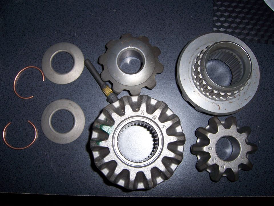 Differential gears, washers, and c-clips laid out on a dark surface