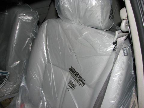 2003 Ford Crown Victoria - The interior of a car features seats still covered in protective plastic, with a Lincoln emblem on the headrest.