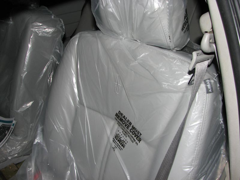 Grey leather Lincoln seats wrapped in dealer plastic covers inside a car
