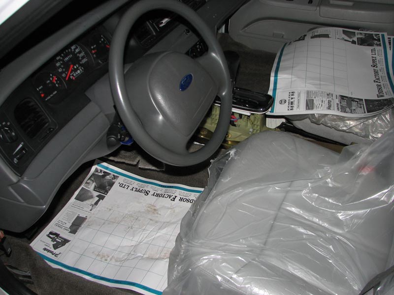 Ford sedan interior mid seat swap with driver seat removed and plastic-wrapped seat