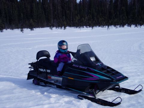 2000 Ford E350 - A child sits on a Polaris snowmobile in a snowy landscape with trees in the background.