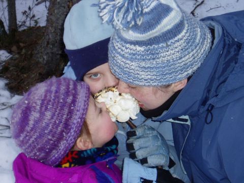 2000 Ford E350 - Three people enjoy a roasted marshmallow together in a snowy outdoor setting.