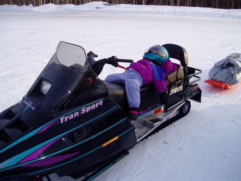 2000 Ford E350 - Child rests on a snowmobile during a winter outing, towing a sled behind.
