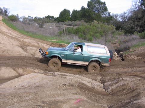 1989 Ford Bronco - This green Ford Bronco tackles a challenging muddy terrain on an off-road course.