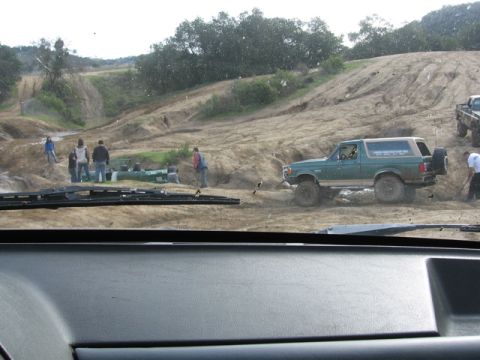 1989 Ford Bronco - 1989 Ford Bronco tackling an off-road trail with spectators present.
